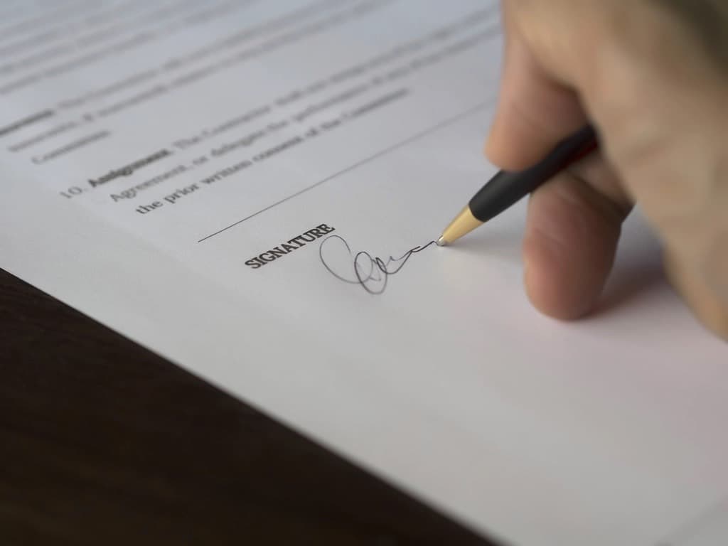 Pessoa assinando um documento sobre a mesa